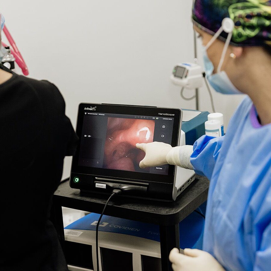 veterinarian wearing scrubs pointing at something on screen during endoscopy procedure