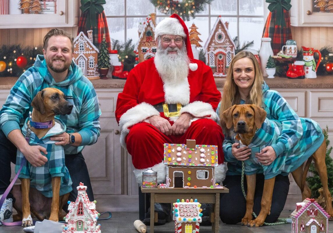 male and female smiling and posing with dogs and santa clause during the Photographs for Santa fundraiser 2025